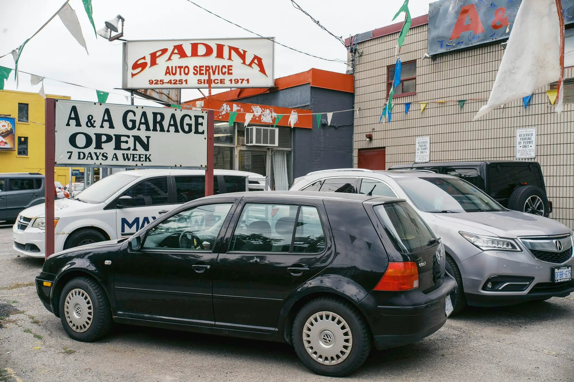 Cars parked outside an open auto service workshop