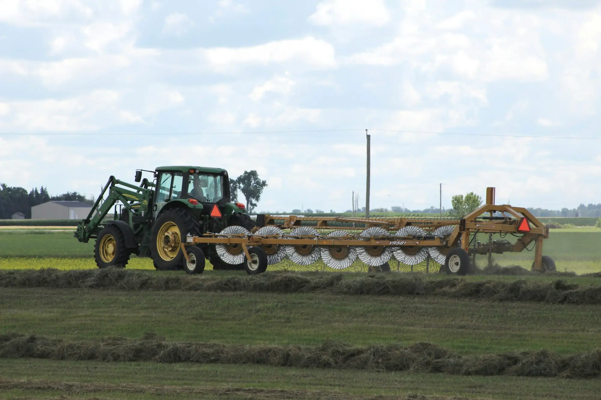 Green tractor working across a grassy paddock, farm machinery funded as equipment